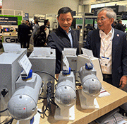 Peening Accessories GmbH介绍其第三代介质流量阀。中国昆山开信精工机械股份有限公司首席执行官陈小虎(左)在展会上推广其产品，并与Abrasive Engineering执行主席S.H. Tan交流。